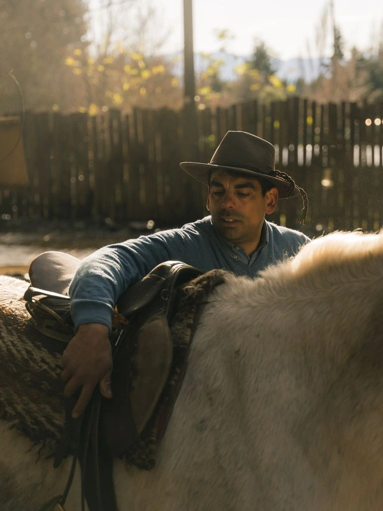 A working rancher in worn denim and canvas, golden-hour portrait at a Texas corral.